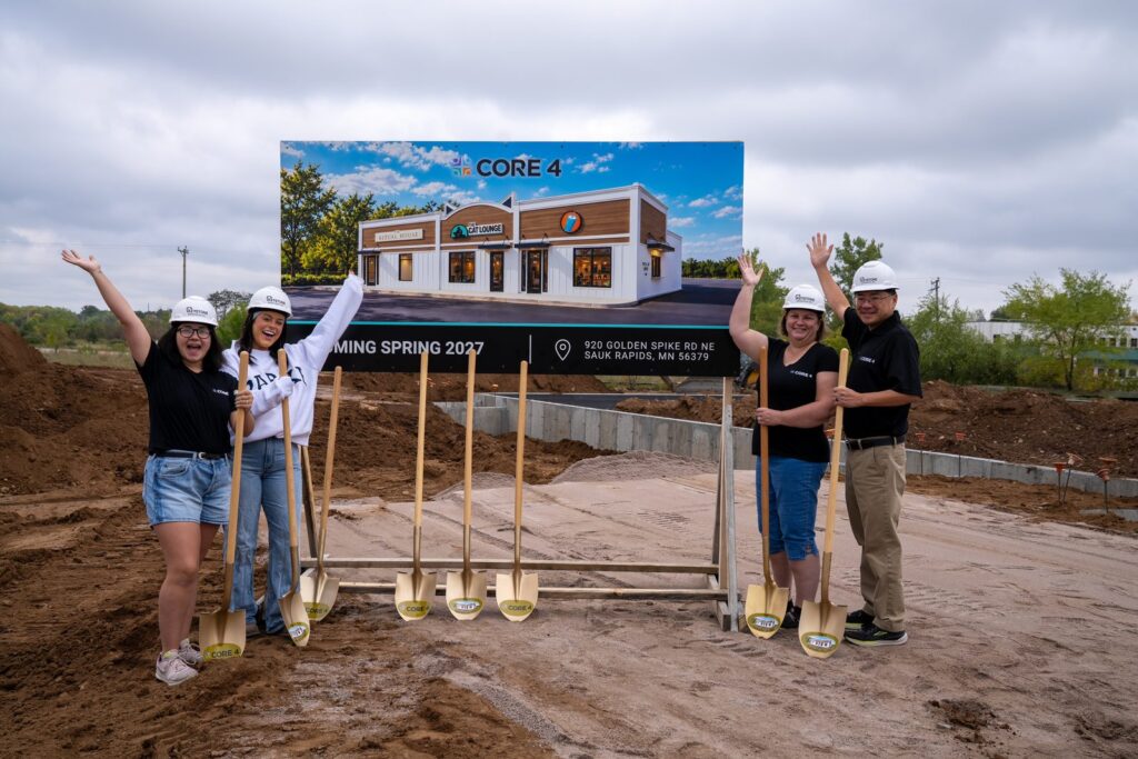 Team members raising their arms in celebration at the groundbreaking